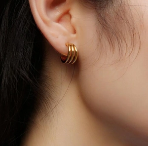 Detail of 18K gold plated titanium steel triple-line curved minimalist stud earring