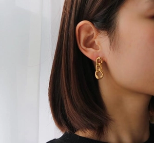 Detail of chunky gold chain hoop earring worn by a model in soft daylight