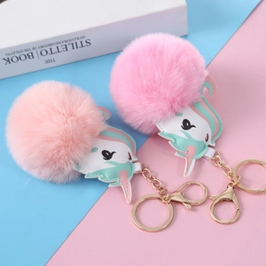 Close-up of pink fluffy unicorn plush ball keychains with metallic gold hardware