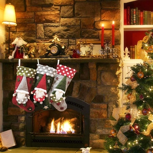 Three lamb wool Christmas stockings with faceless gnomes hanging by a cozy fireplace