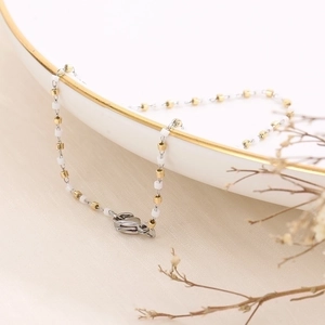 Detail of colorful drip oil gold chain with white beads and silver lobster clasp