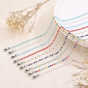 Detailed macro shot of colorful enamel bead chains with lobster clasps on a ceramic plate