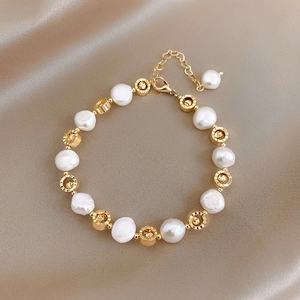 Baroque pearl and gold openwork bead bracelet with adjustable chain on champagne velvet