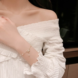 Elegant adjustable gold bracelet with bow pendant and white pearls for women