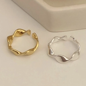 Minimalist wavy twisted open rings in gold and silver finish for women on white surface