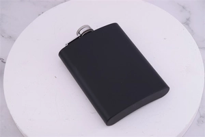 Detail of matte black stainless steel flask with silver screw cap on marble base