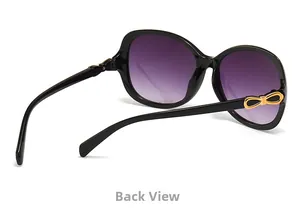 Close-up of golden bow detail on black vintage sunglasses with purple gradient lenses