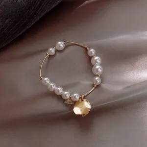 Detail of gold pearl bracelet with brushed metal coin and star moon charms on silk fabric