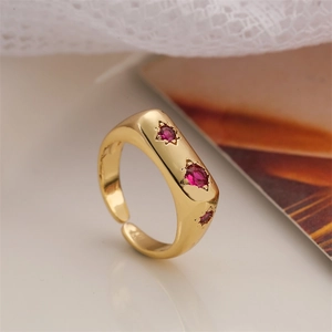 Macro detail of gold adjustable ring featuring three red zircons in star-shaped settings