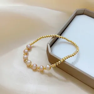 Detailed shot of golden beaded bracelet with champagne pearls on silk texture