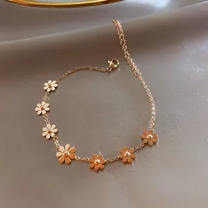 Detail of rose gold daisy bracelet featuring seven floral charms on silk background