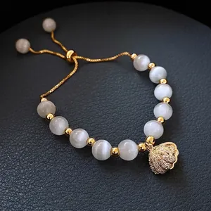 Detail of adjustable pearl bracelet with shell charm and gold beads on leather background