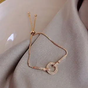 Macro detail of adjustable gold bracelet with zircon geometric charms on silk fabric