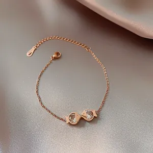 Macro shot of rose gold stainless steel bracelet featuring zircon fish charms on satin