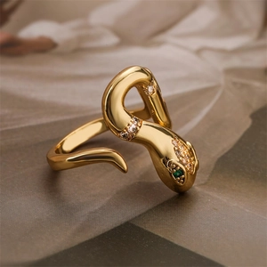 Close-up of a gold snake ring with green zircon eyes and clear crystal inlay on fabric