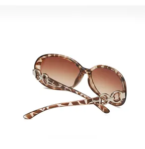 Detail of leopard print sunglasses featuring silver chain hardware and brown gradient lenses