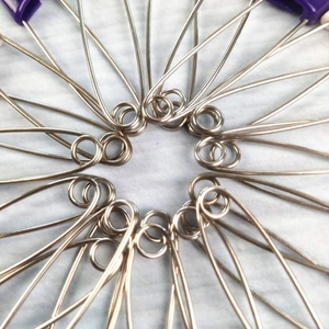 Dettaglio di spille di sicurezza in plastica viola e metallo disposte a raggiera