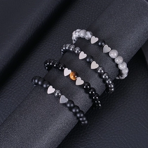 Detailed view of beaded bracelets with heart pendants on a textured black display