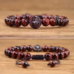 Detail of red tiger eye bead bracelet with a black lion head charm and adjustable cord knot