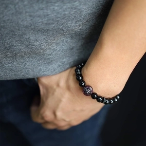 Close-up of beaded tiger eye bracelet with lion head charm on a male model's wrist