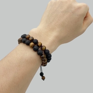 Detail of 8mm green tiger eye and lava stone double-layer beaded bracelet on a wrist
