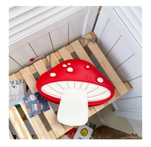 Detailed view of the red mushroom crossbody bag with silver chain on wood background