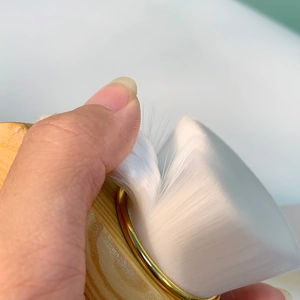 Detailed close-up showing density of soft white bristles on the wooden facial brush