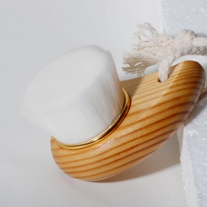 Macro detail of wooden facial brush with soft white bristles and gold metal ring