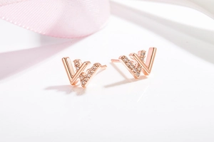Macro shot of rose gold letter W earring with sparkling cubic zirconia on white background