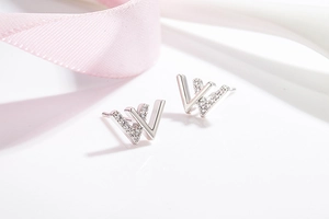 Close-up of minimalist silver letter W stud earrings with sparkling zircon inlay detail