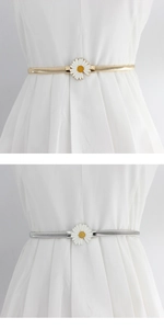 Detail of elastic metal belts featuring large white daisy buckles in gold and silver