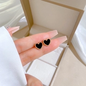 Detailed view of heart-shaped earrings featuring black shell inlay and gold bead edges