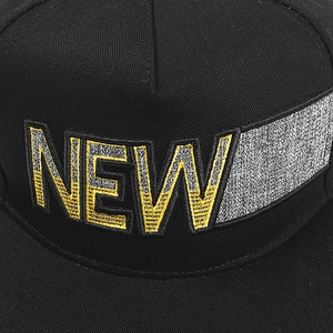 Détail de la broderie NEW avec coutures argent et jaune sur une casquette hip hop noire