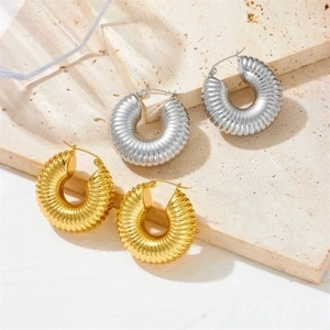 Golden and silver chunky hoop earrings with textured ribbing on stone background