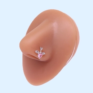 Macro shot of L-shaped nose stud with pink heart zircon and silver wings on model