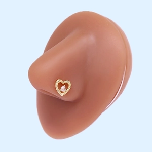 Macro shot of heart-shaped gold nose stud with pink zircon on a silicone nose model