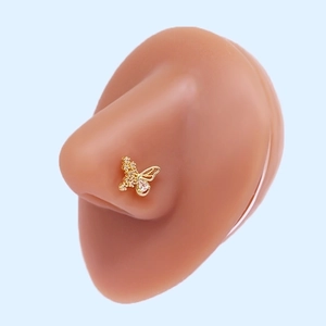 Macro shot of gold butterfly nose stud with cubic zirconia on silicone model