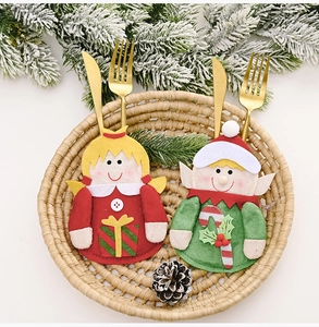 Detail view of angel and elf felt cutlery holders on a festive woven tray with pine cones
