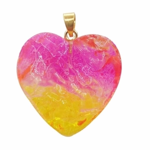 Close-up of heart-shaped gradient crystal pendant in pink and yellow with gold clasp