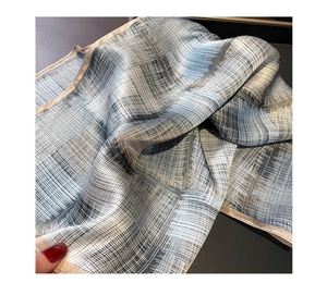 Close-up of grey-blue striped silk scarf texture with soft geometric grid patterns