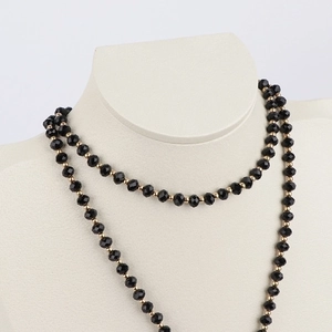 Elegant black faceted beads and gold metal spacers on a beige neck display stand