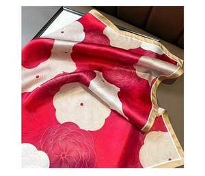 Macro detail of a red and white floral silk square scarf with golden borders on leather