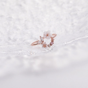 Macro detail of rose gold open ring with white flower and sparkling zircon gemstones