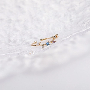 Close-up of gold branch ring with colorful zircon crystals on an ice-crackled glass edge