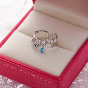 Close-up of silver flower ring with micro-pave crystals and blue teardrop gem in a red box
