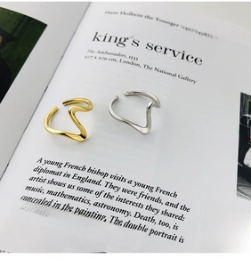 Nahaufnahme von minimalistischen Wellenringen in Gold und Silber auf Kunstzeitschriften