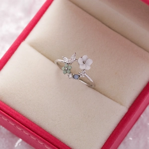 Detailed view of floral ring with resin petals and blue crystals on velvet