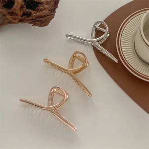 Three large metal shark hair claws in silver, gold, and rose gold with cross line design
