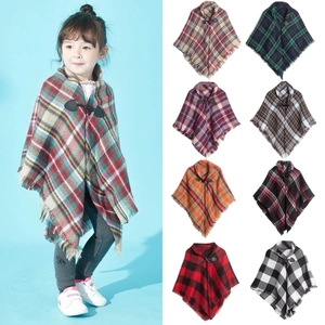 Detail of colorful plaid kids poncho with toggle closure and fringe edge in various colors