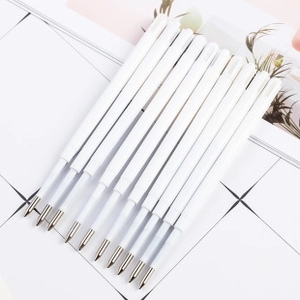 Macro shot of 11 white replacement pen refills with polished metal tips for ballpoint pens